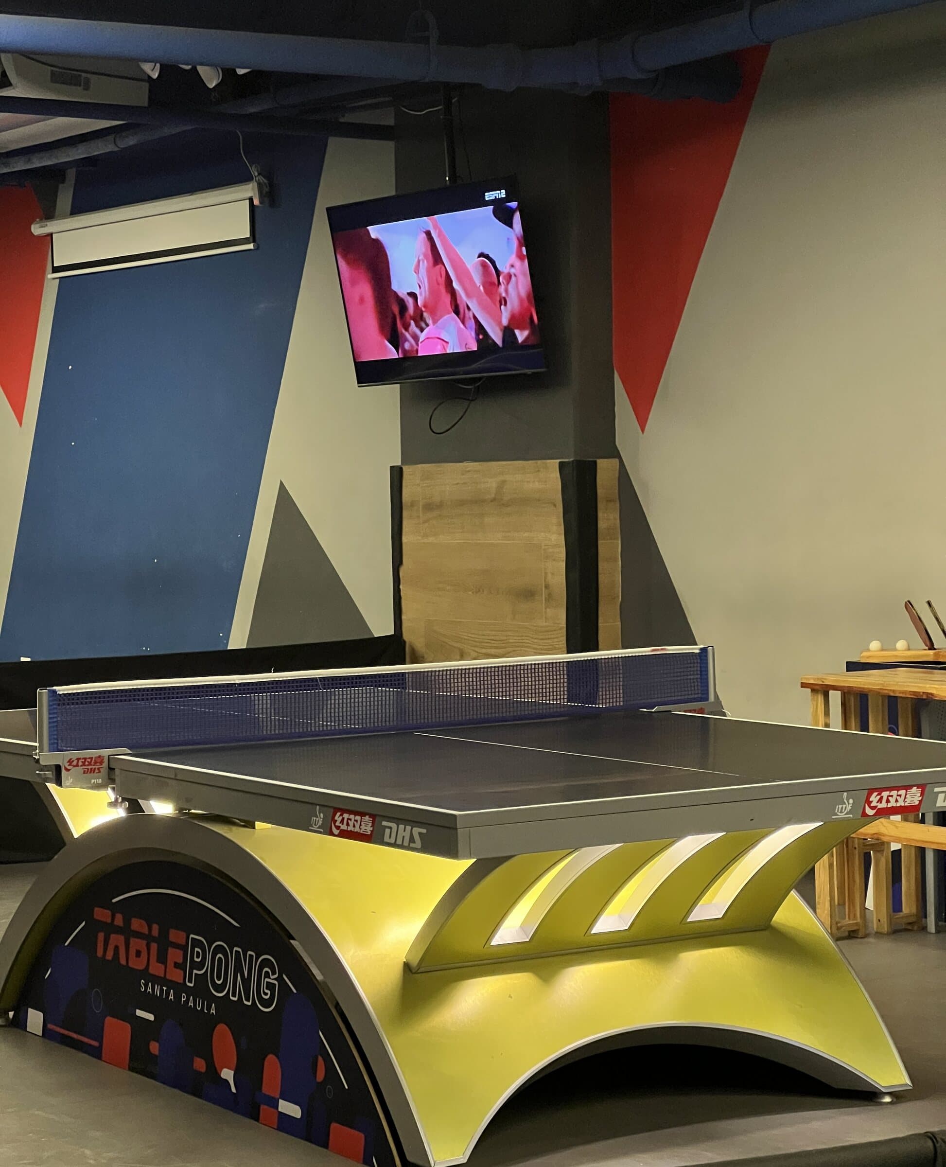 Mesa amarilla con TV deportiva al fondo
