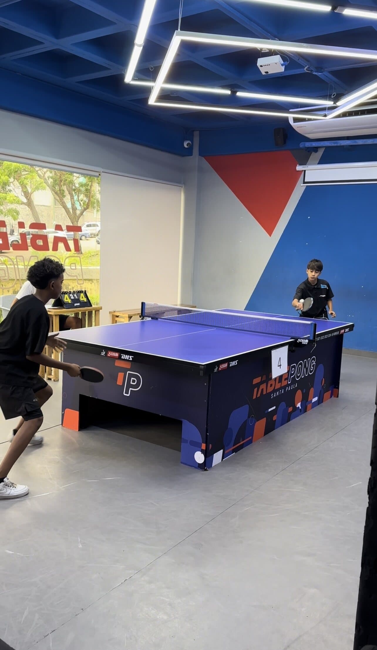 Jugadores jóvenes en mesa azul de tenis de mesa